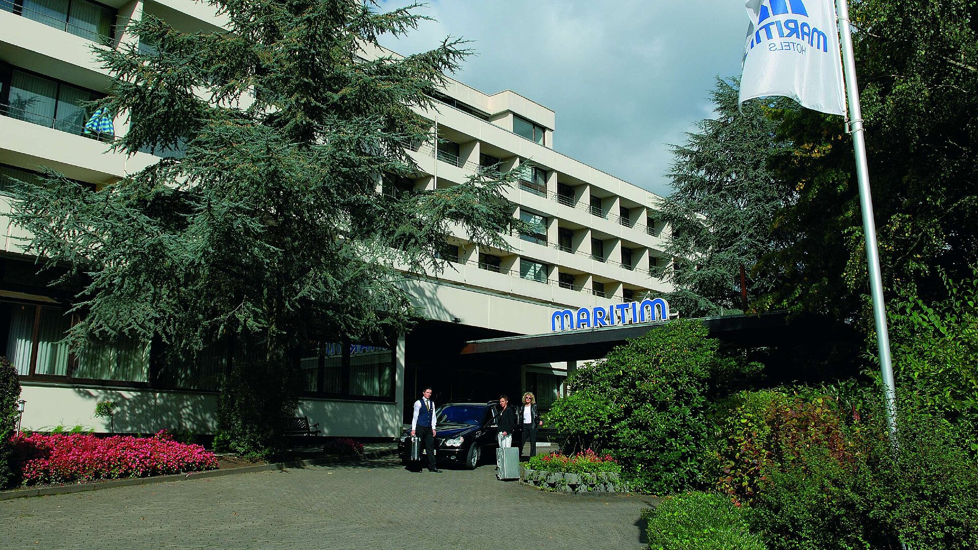 Eingang des Hotels äste treffen am Eingang des Maritim Hotel Bad Salzuflen ein, umgeben von Bäumen und gepflegtem Grün